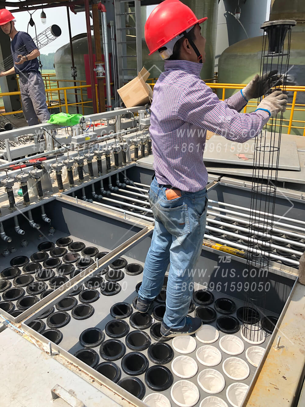 Technicians handling round filter bag cages beside the tube sheet during a PPW series baghouse installation