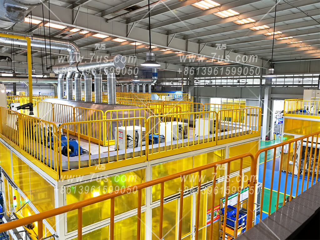 Overhead hoods and branch ducts joining a shared main duct above robotic welding enclosures